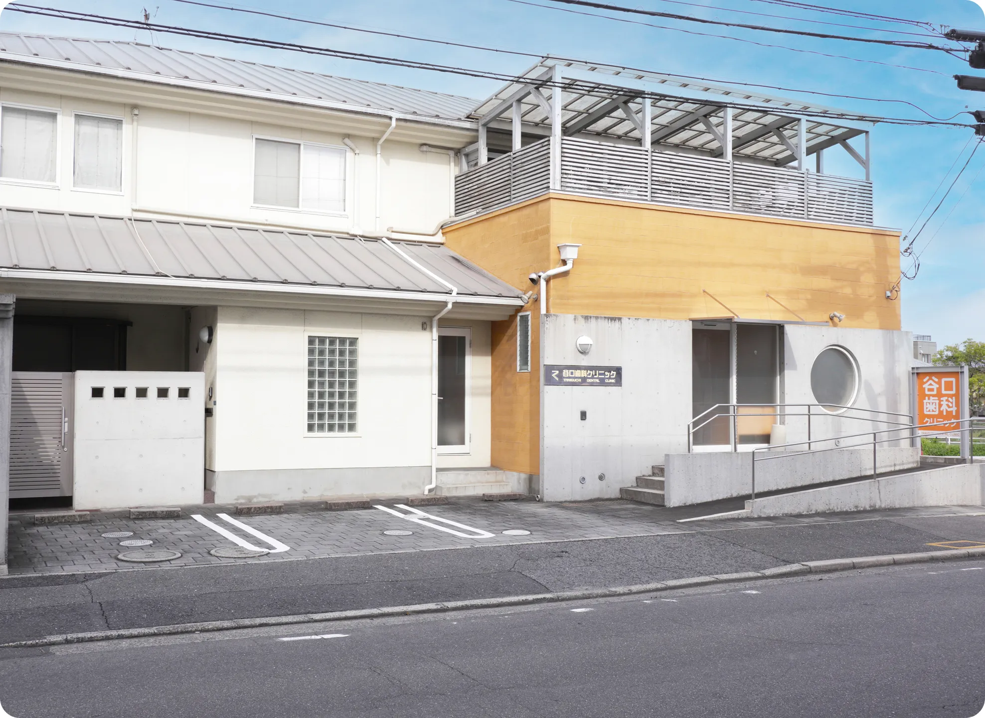 谷口歯科クリニックの外観・入り口の様子。オレンジ色の壁が特徴です。