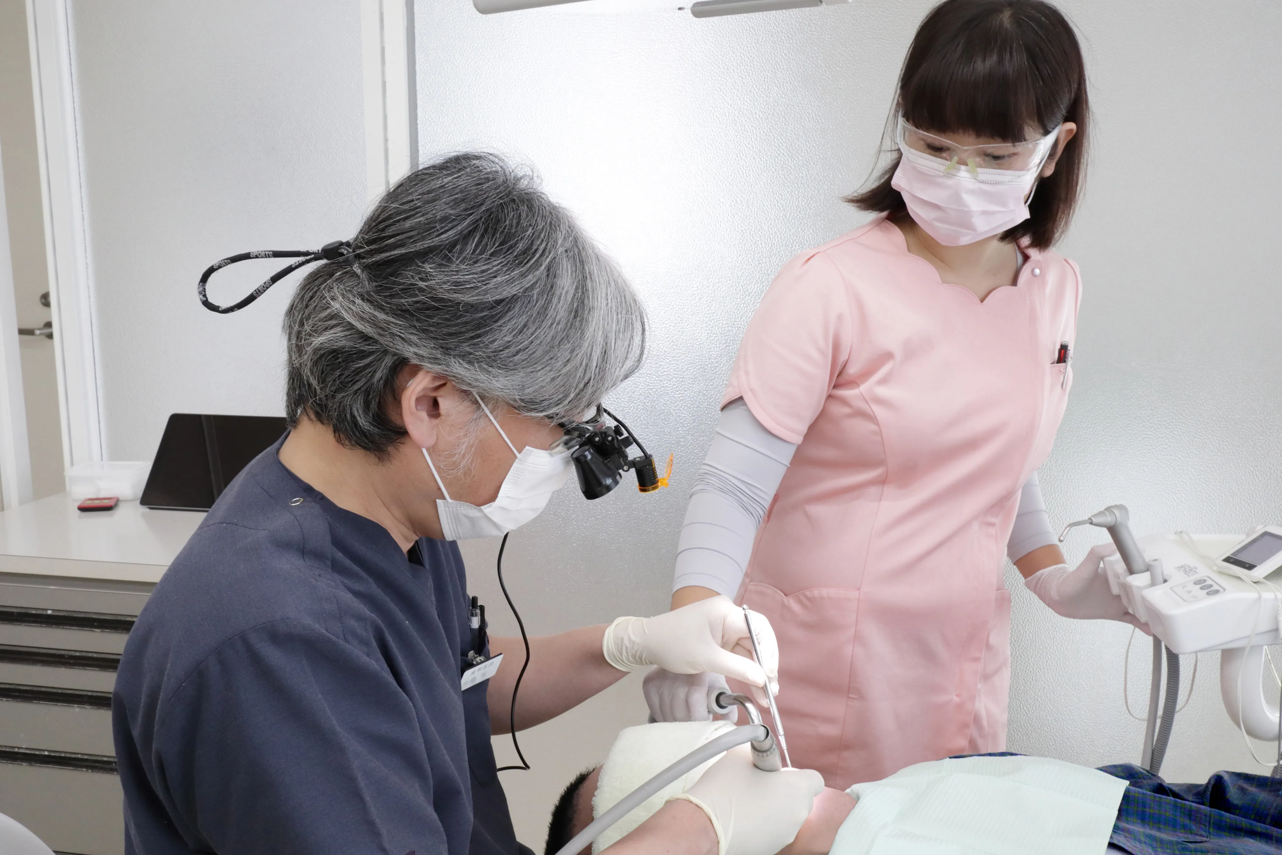 診療室にて、男性歯科医による丁寧な治療風景